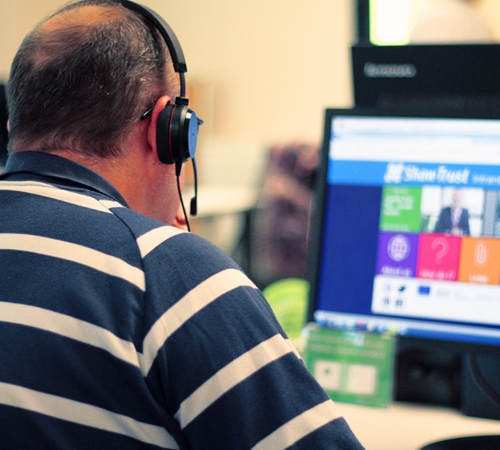 An Accessibility Assessor sat in front of his computer, wearing a headset