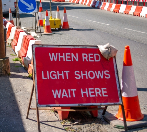 temporary traffic lights with a sign reading "when red light shows wait here"