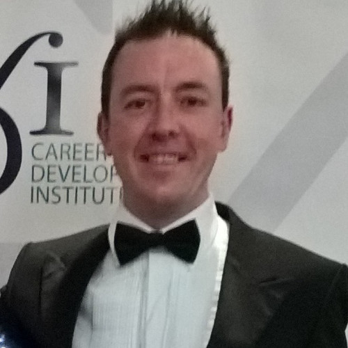 Mark Mitchell, who has short brown hair, is smiling whilst wearing a black suit and dickie bow at an award's event.