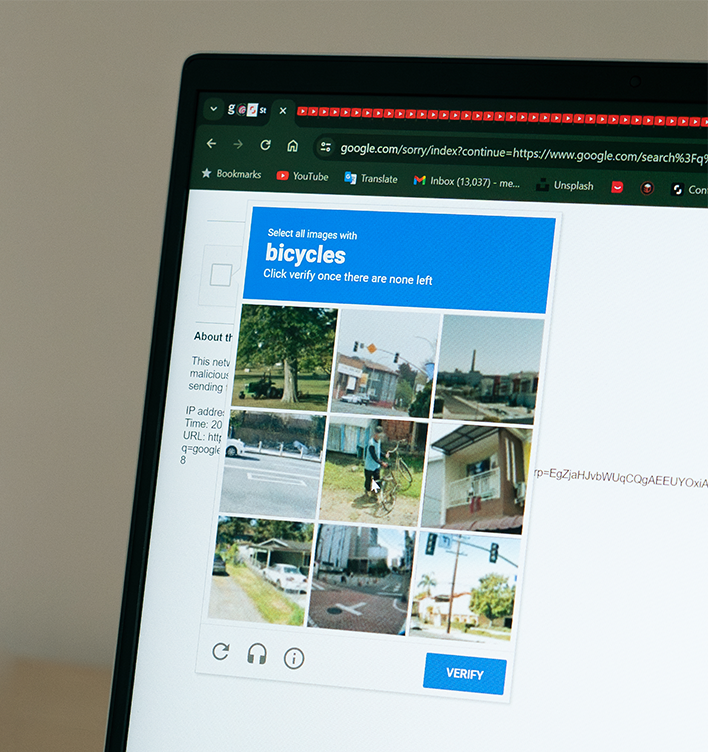a monitor is displaying a website CAPTCHA, which has multiple images on display and is asking the user to select the squares which have bicycles in them.